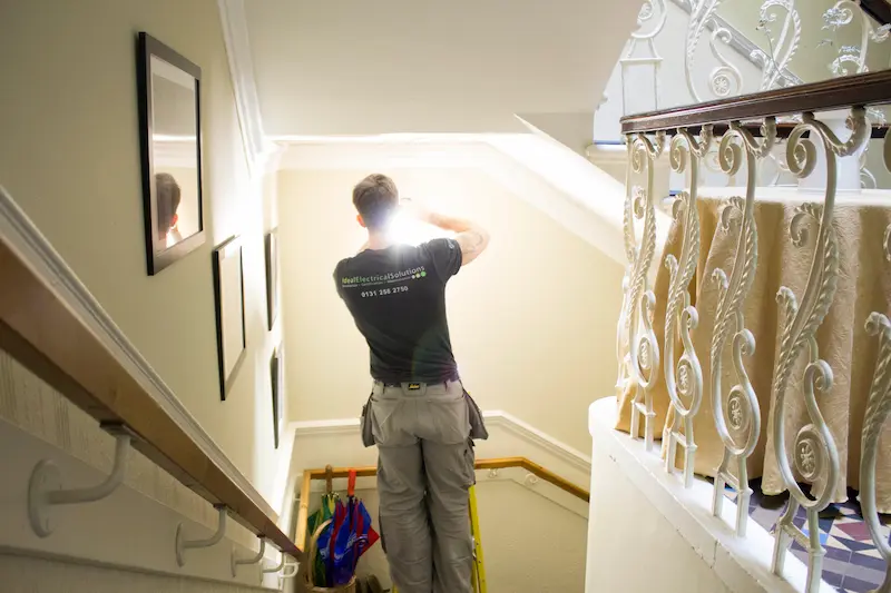 IES electrician working on stair lighting repairs in Edinburgh.