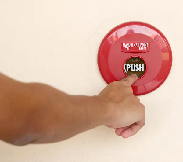 Pushing the button as part of the fire alarm test.