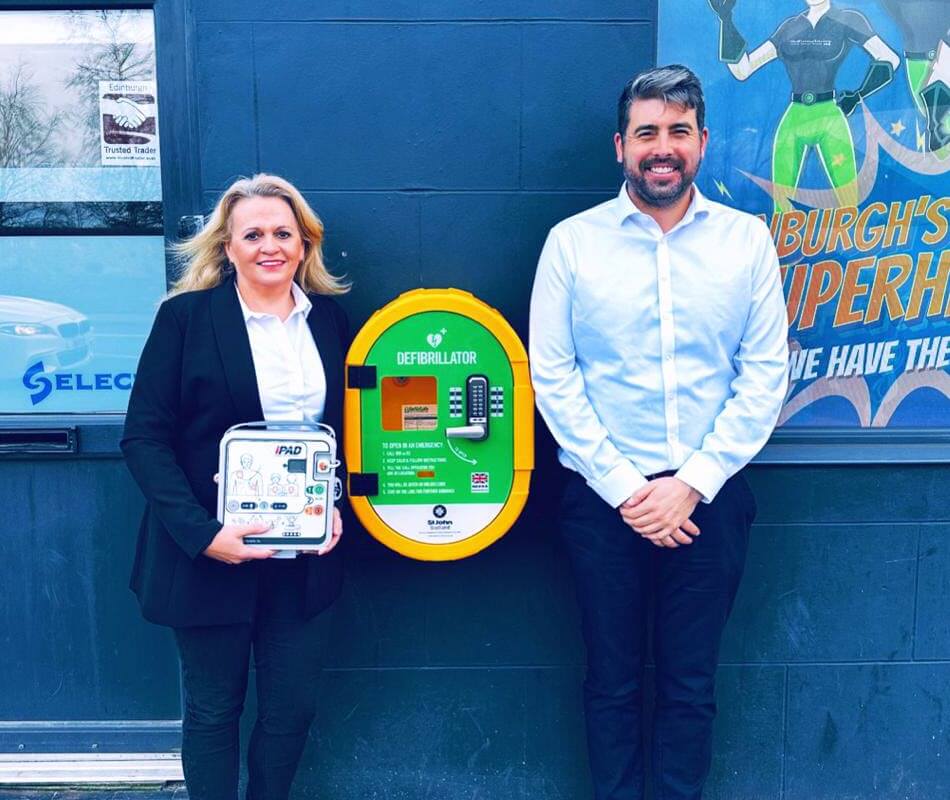 Mark & Lisa with the new defibrillator cabinet installed in Meadowbank Edinburgh.