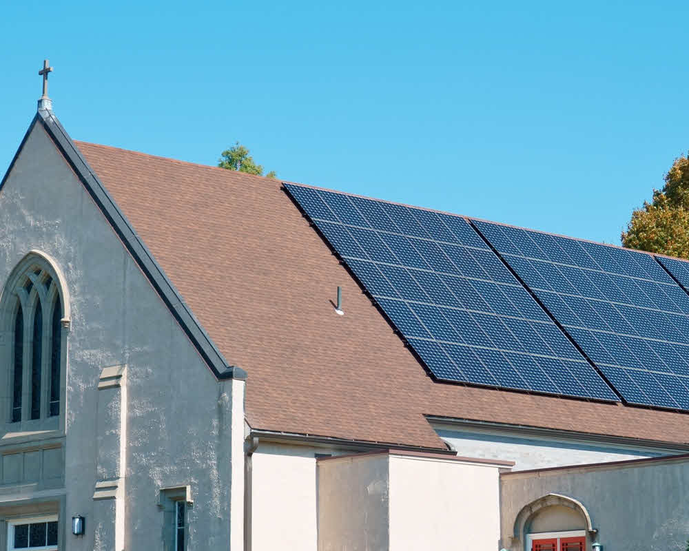 Commercial solar panels installed on church roof and generating renewable energy.